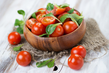 Wooden bowl with fresh cherry tomatoes and corn salad leaves