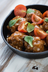 Cast-iron frying pan with meatballs, close-up