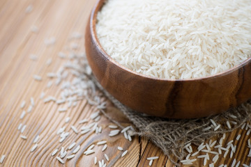 Raw basmati kernels in a wooden bowl, horizontal shot