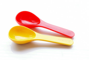 yellow spoon and red fork on white background