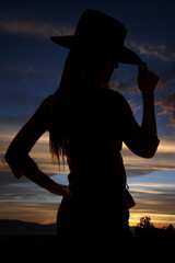 silhouette of cowgirl tipping her hat at sunset