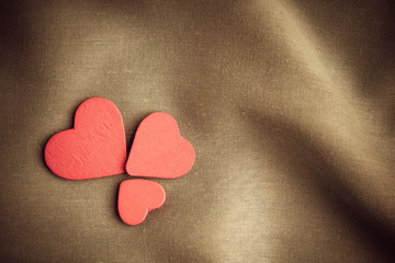 Red wooden decorative hearts on brown folds background.