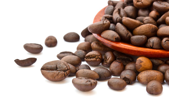 Fresh coffee beans with wooden spoon isolated over white