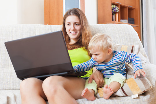 Smiling mother with baby working online