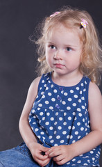 Naklejka premium serious little girl 3 years old, on dark background.