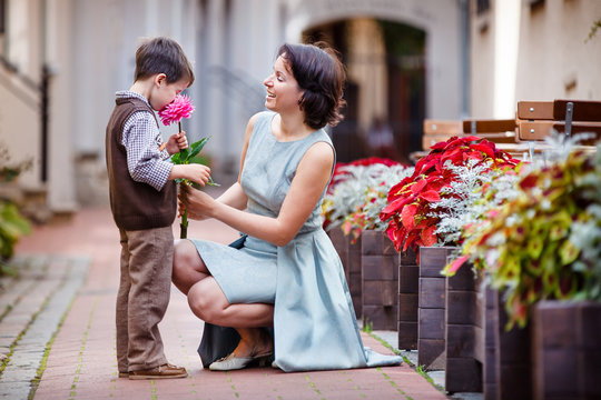 Little boy giving flower to his mom
