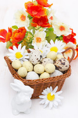 wicker basket with easter eggs, flowers and white rabbit
