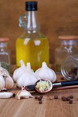 Fototapeta na wymiar Composition with garlic press, fresh garlic and glass jars with