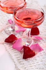 Composition with pink sparkle wine in glasses and rose petals