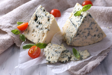 Tasty blue cheese with tomatoes and basil on paper