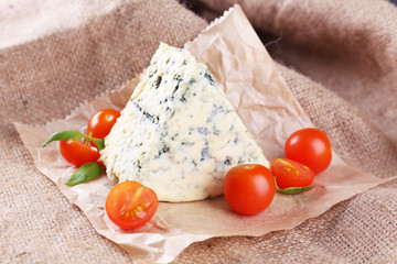Tasty blue cheese with tomatoes and basil, on burlap background