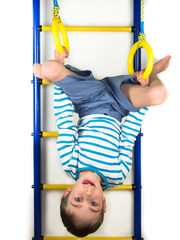 Child hanging upside down on the rings on a white background