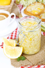 Tasty lemon jam with cup of tea on table close-up