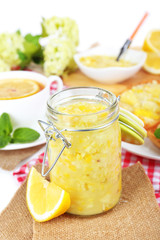 Tasty lemon jam with cup of tea on table close-up