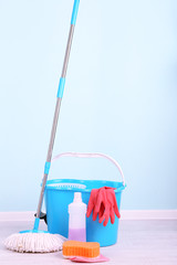 Floor mop and bucket for washing in room on blue wall