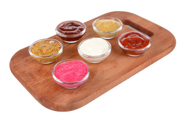 Various sauces on chopping board isolated on white