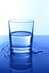 Water in  glass, on blue background