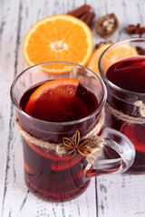 Mulled wine with oranges and spices on wooden background
