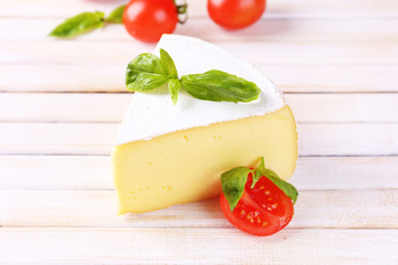Tasty Camembert cheese with basil and tomatoes, on wooden table