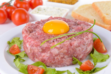 Delicious steak tartare with yolk on plate on table close-up