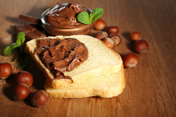 Bread with sweet chocolate hazelnut spread on wooden background