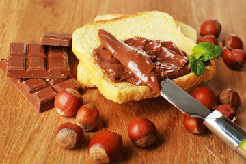 Bread with sweet chocolate hazelnut spread on wooden background