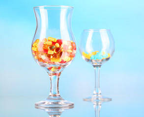 Goblets with pills on blue background