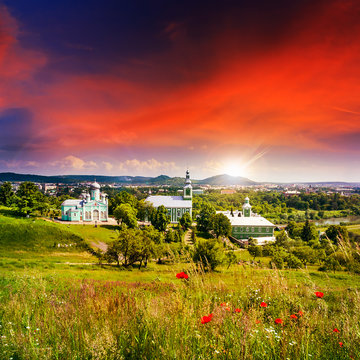 red poppy flowers and the green monastery at sunset