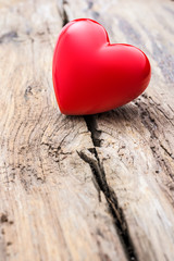 Fototapeta premium Red heart in crack of wooden plank
