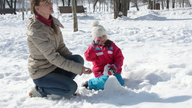 Happy woman and child playing with snow