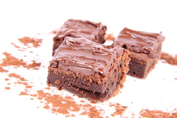 Slices of a brownie on white background covered with chocolate