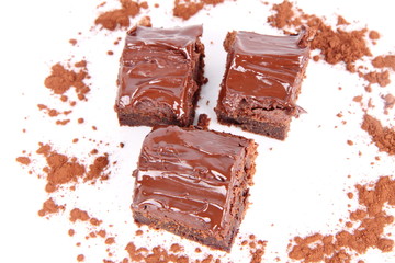 Slices of a brownie on white background covered with chocolate