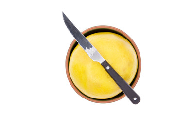 Kitchen knife on a ripe yellow grapefruit