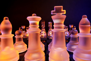 Glass chess on a chess board lit by blue and orange light