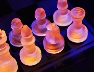 Glass chess on a chess board lit by blue and orange light