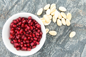 Seeds of fresh pomegranate, next to peeled almonds