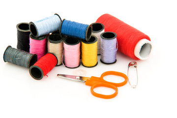 closeup of multicolored sewing spools and scissors on white