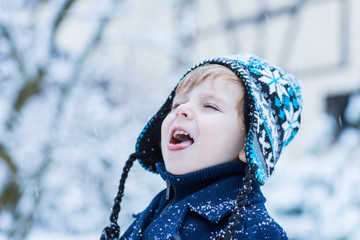 Little toddler boy having fun with snow outdoors on beautiful wi