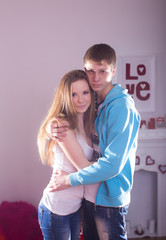 Beautiful young smiling couple in love embracing indoor