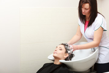 Fototapeta premium Hairstylist washing woman hair. Hairdressing beauty salon