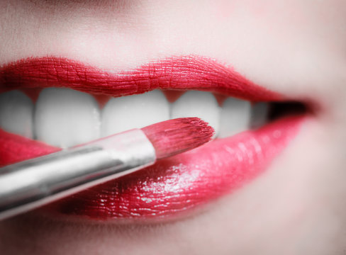Closeup female red pink lips with makeup lipstick brush