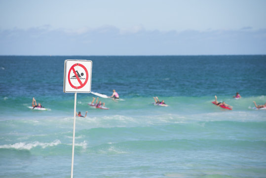 Swimming prohibited sign with surfer in ocean