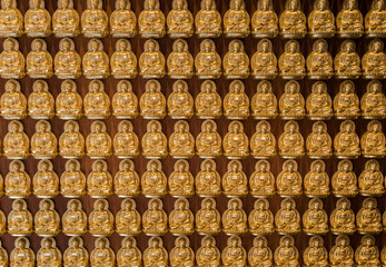 Fototapeta premium golden buddhas lined up along the wall of chinese temple