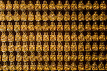 golden buddhas lined up along the wall of chinese temple