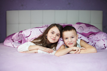 siblings having fun in bed before sleeping, two happy friends - 61300714