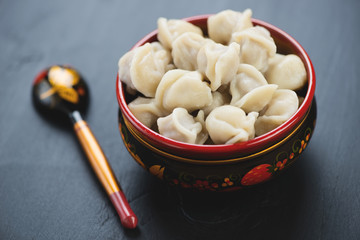 Boiled pelmeni or meat dumplings on a dark wooden background