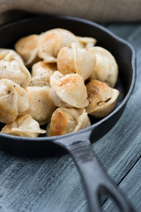 Cast-iron pan with fried pelmeni or meat dumplings, close-up
