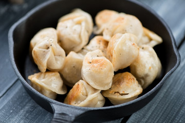 Fried pelmeni in a cast-iron pan, close-up, horizontal shot