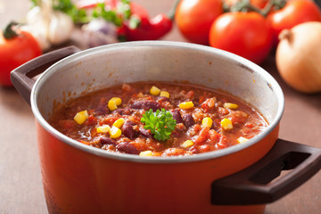 mexican chili con carne in red rustic pot with ingredients