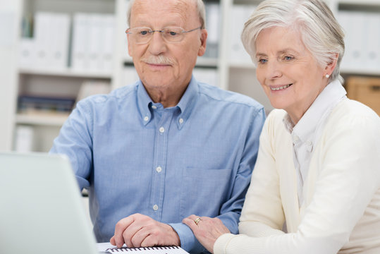älteres ehepaar schaut auf laptop
